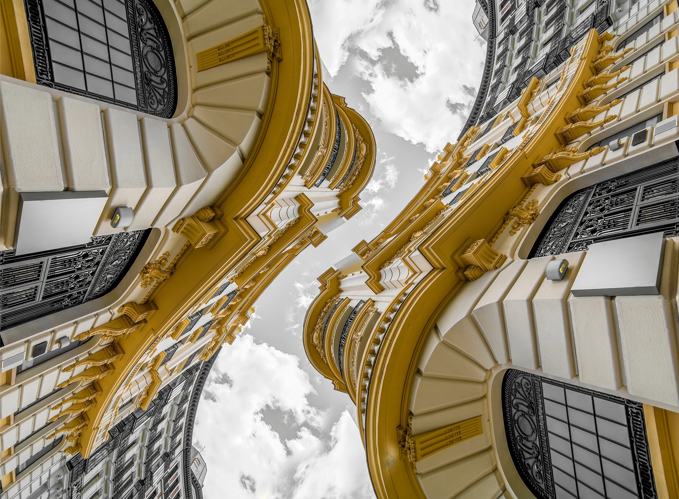 Architectural detail in white and golden yellow, looking toward the sky